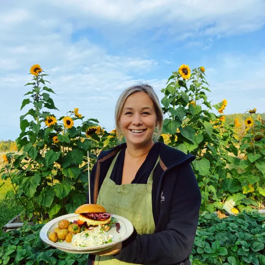 Josefin visar upp en tallrik mat framför solrosor