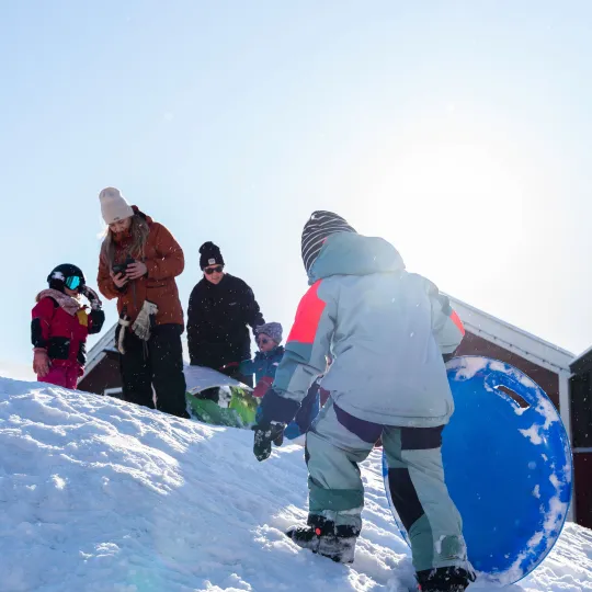 Barn går upp för en snöbacke med ett tefat