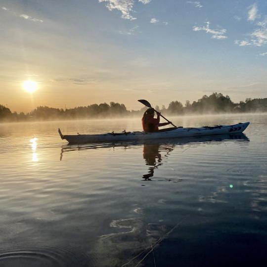 Paddla kanot i morgondis när solen går upp