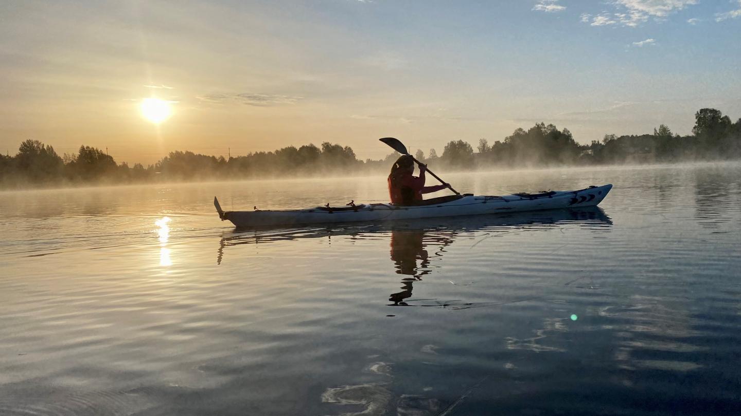 Paddla kanot i morgondis när solen går upp